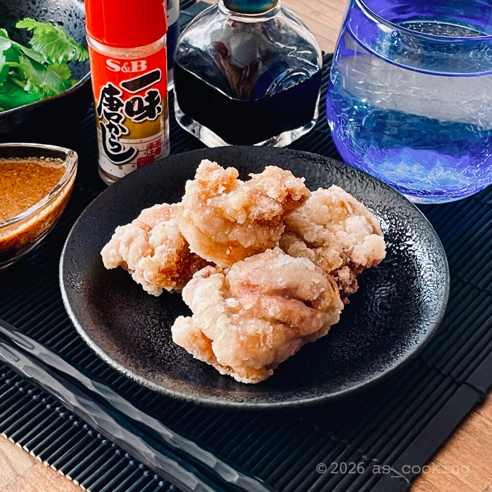 カリッと揚げた鶏肉の唐揚げと、器に添えたごまだれの給食メニュー風盛り付け