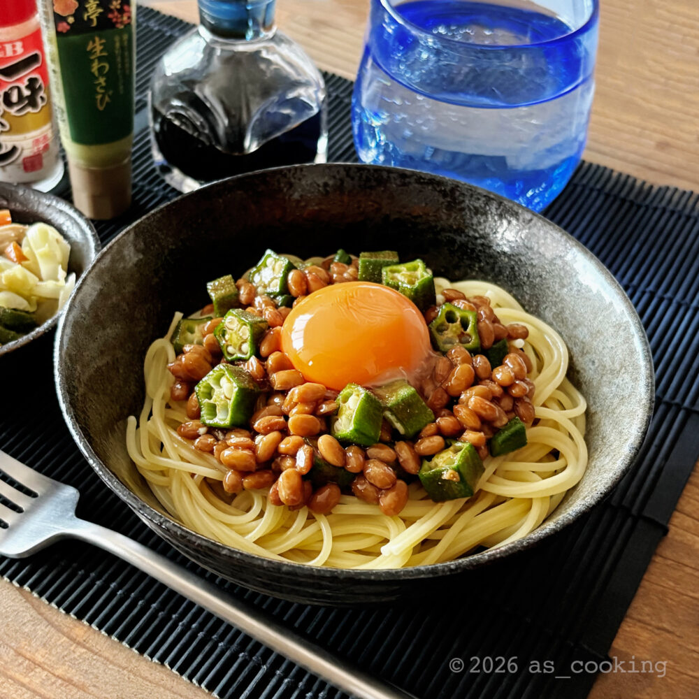お皿に美しく盛り付けた細めパスタの上にたっぷりの納豆とオクラと濃厚な卵黄をのせたネバネバパスタ