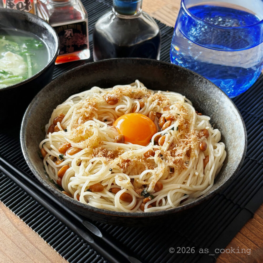 茹でたそうめんに特製納豆ダレと卵黄をのせ、レンジで加温して粉々にした鰹節をかけた納豆油そうめん