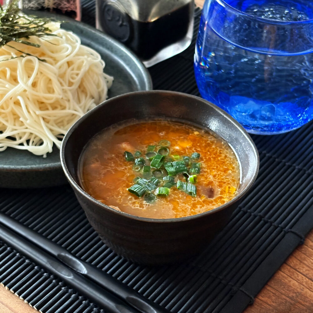 器に入った納豆と卵黄のつけダレと盛られたそうめん