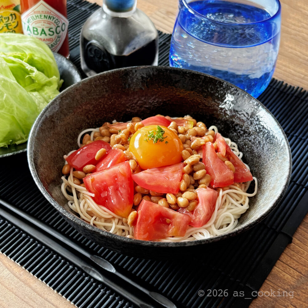 器に盛り付けられたトマトと納豆の上に卵黄がのったピリ辛そうめん