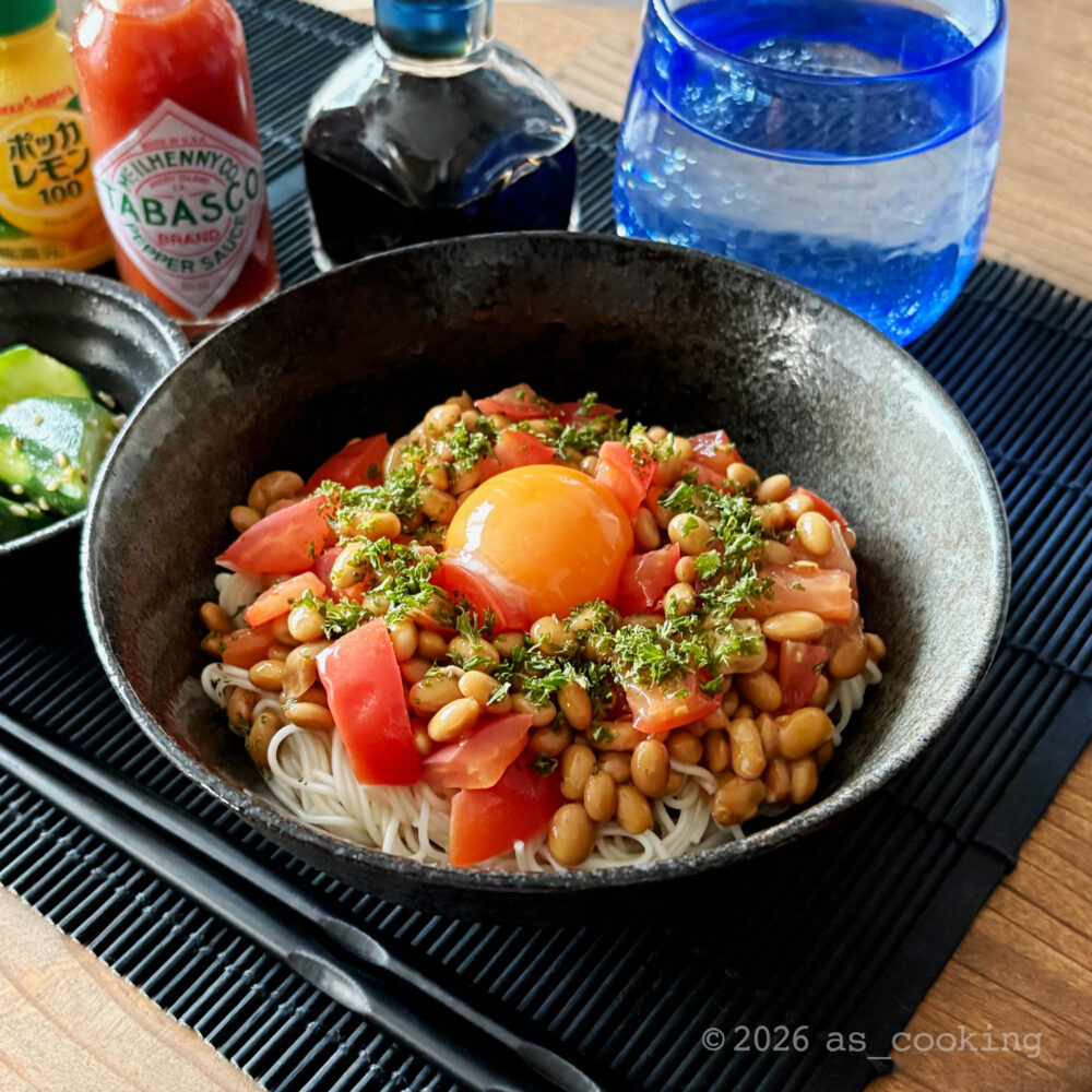 茹でたそうめんに小さくカットしたトマトと納豆をかけ、中央に卵黄とイタリアンパセリをのせたトマト納豆そうめん