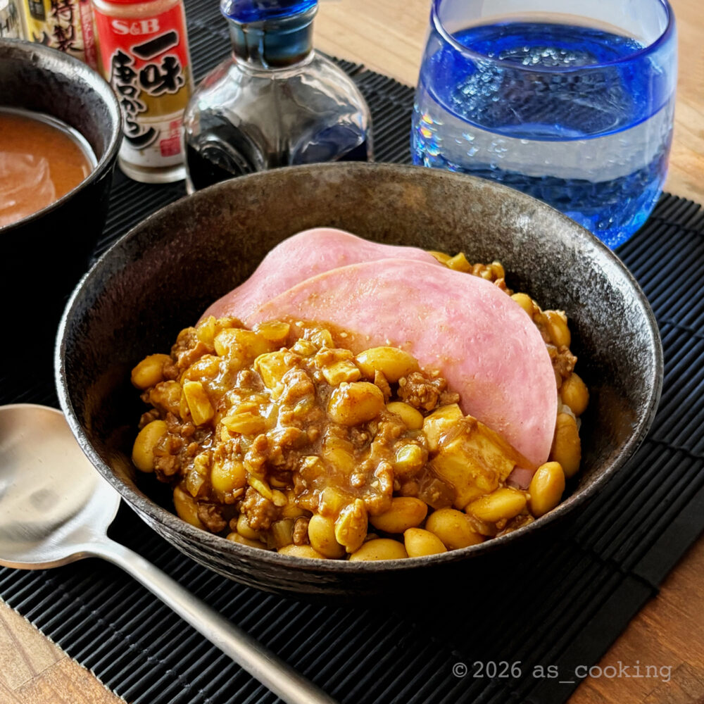 温かいご飯の上に大豆や豆腐入りのカレー風味のソイ丼の頭をかけ、ハムをのせたソイ丼